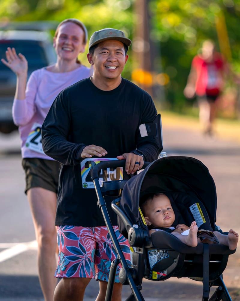 A dad pushes a baby in a running stroller