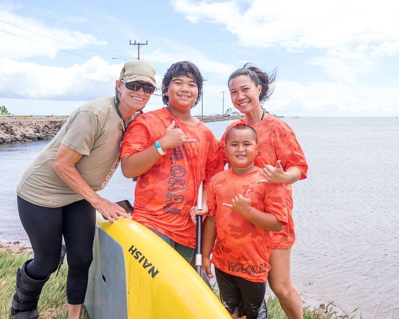 A volunteer and keiki with paddleboards at the shoreline