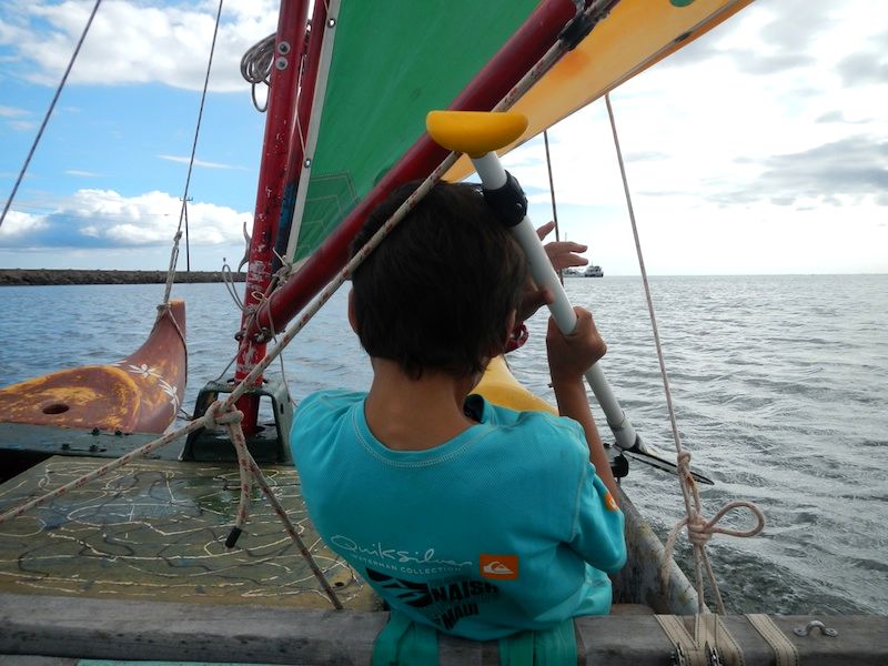 A keiki steers an outrigger sailing canoe off Molokaʻi