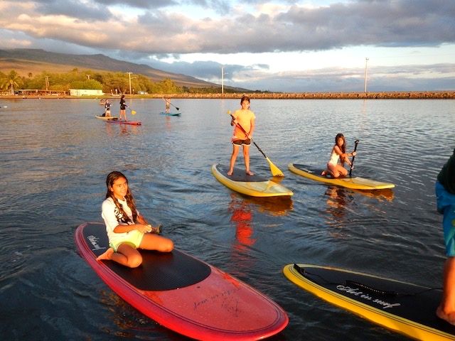 Keiki on stand-up paddleboards in the harbor at sunset